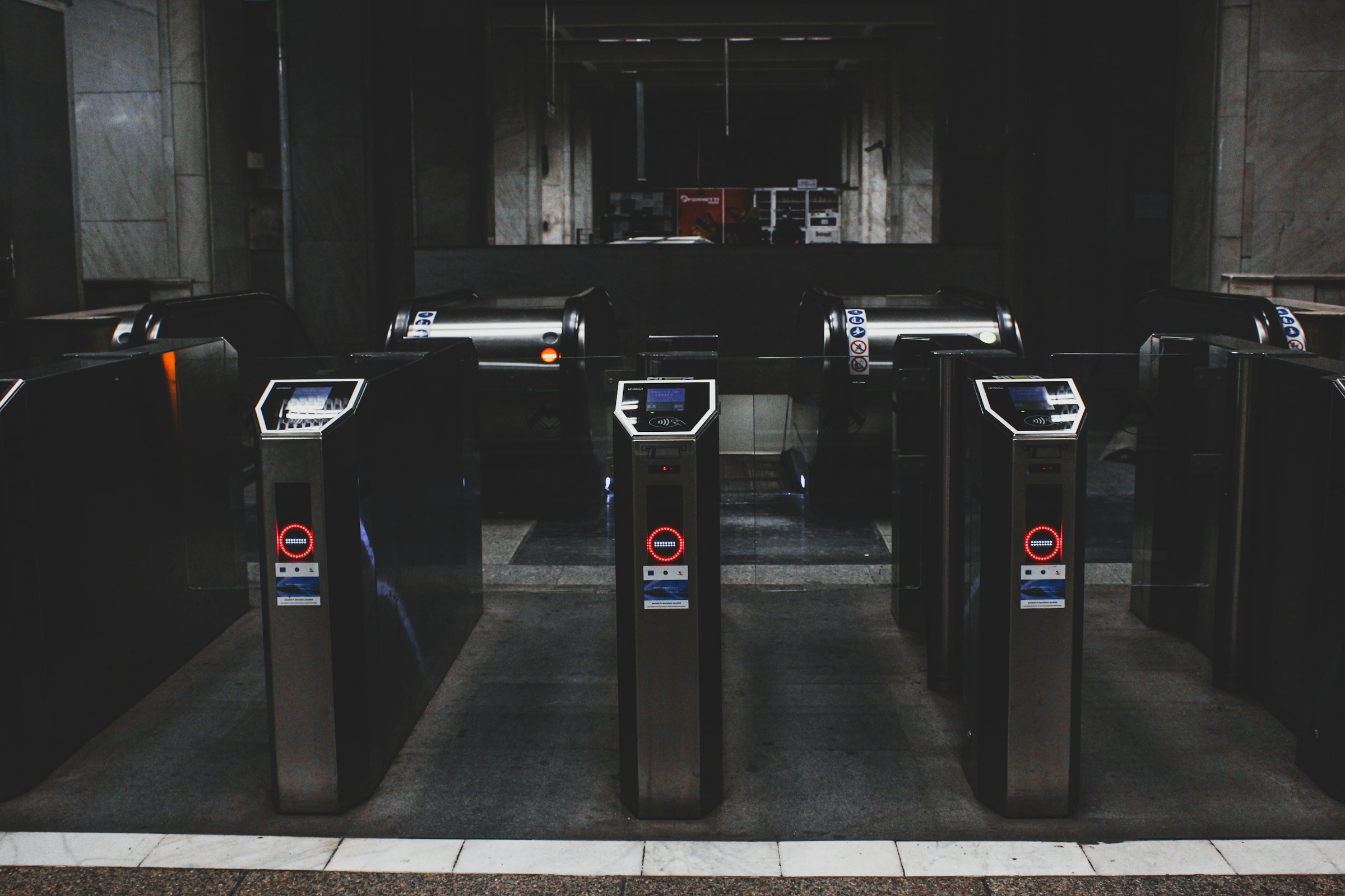 A row of black metal turnstiles in a building lobby